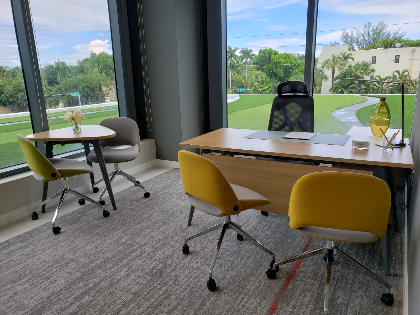 Premium private office with large desk, yellow chairs and garden view